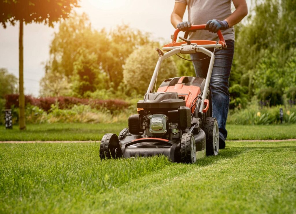 Person mowing a lush green lawn