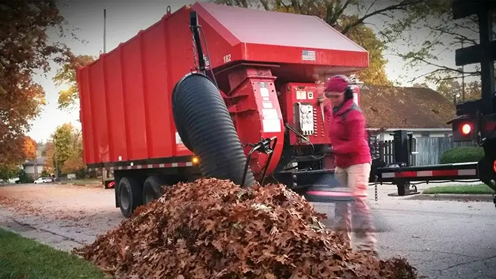 An MJR worker sucking up curbside leaf piles from MJR customers.